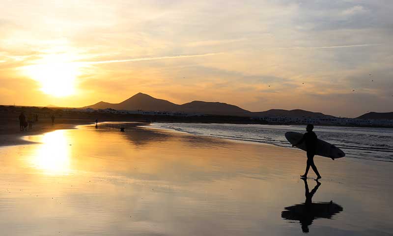 Puesta de sol con un surfista paseando