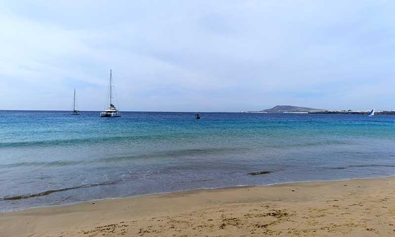 Foto de una playa con un barco al fondo