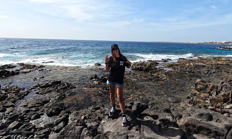 Chica en las rocas con el mar al fondo