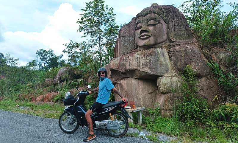 chico en moto con escultura de buda