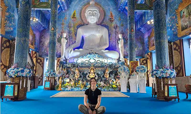 Chica delante de la figura del buda en el templo azul de Chiang Rai