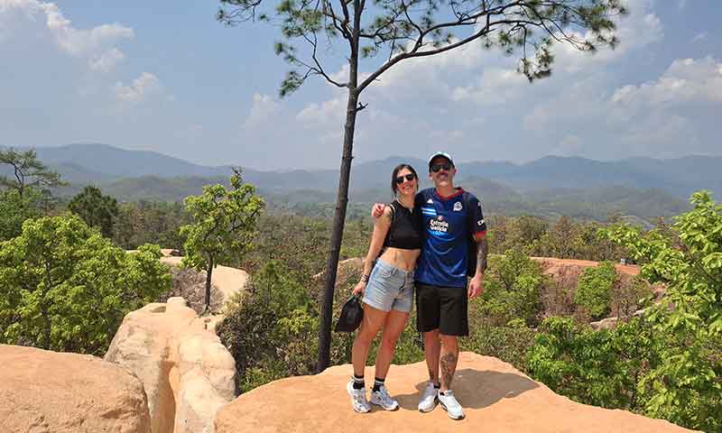 Pareja posando en un sendero elevado del Cañón de Pai Kong Lan en Tailandia con vistas a las montañas