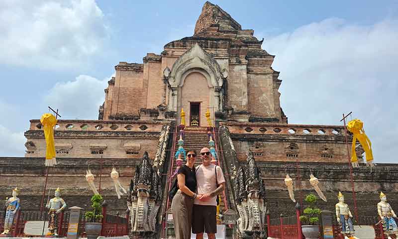 Pareja viajera posando frente a la gran estupa de piedra del templo Wat Chedi Luang en el centro de Chiang Mai