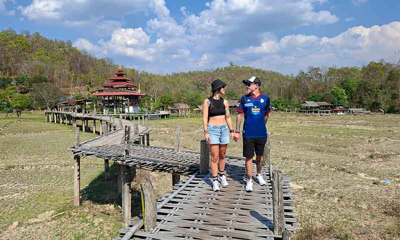 Pareja caminando sobre el puente de bambú Bamboo Bridge Boon Ko Ku So sobre campos en Pai Tailandia